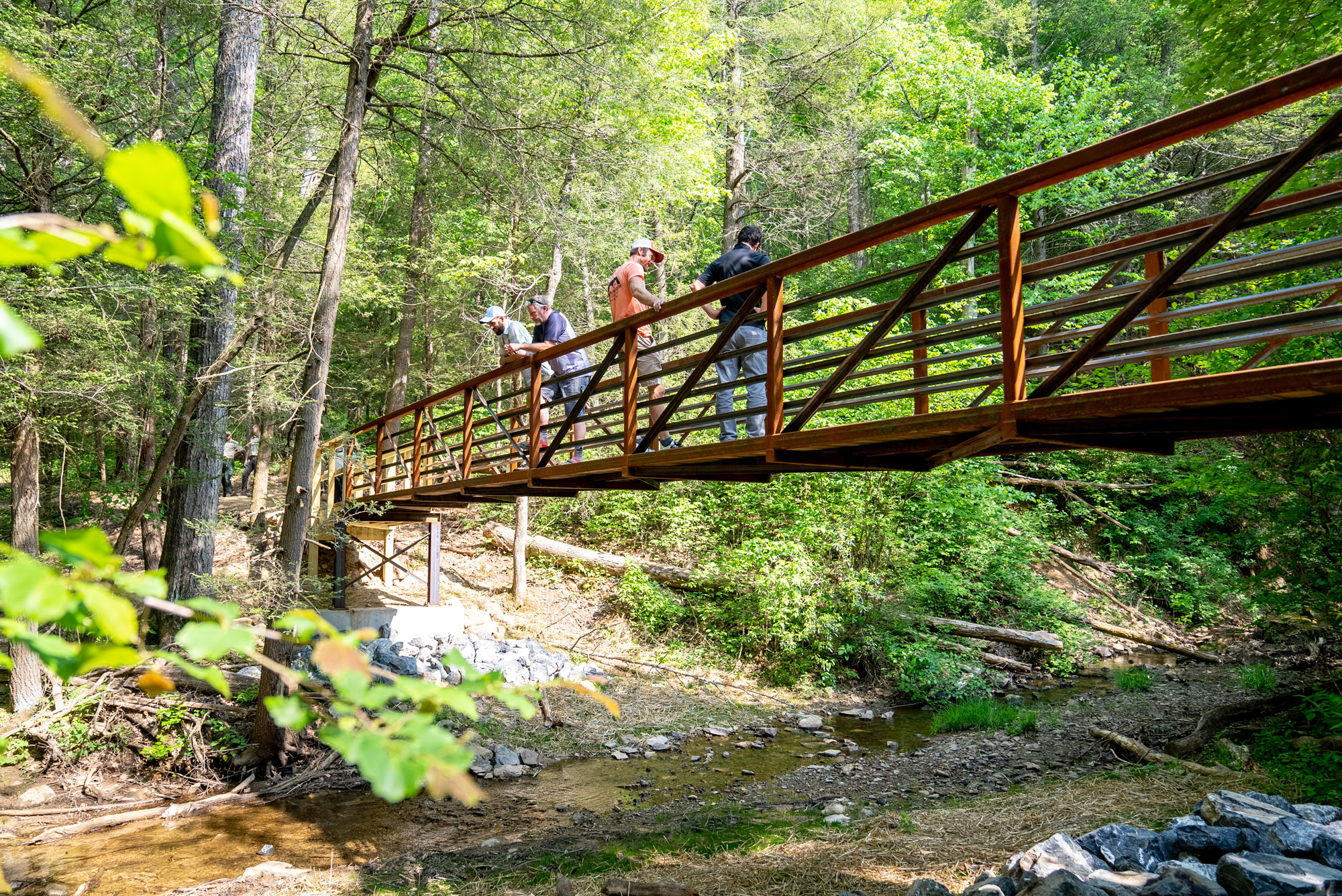 Photograph of hikers standing on newly constructed bridge over water.