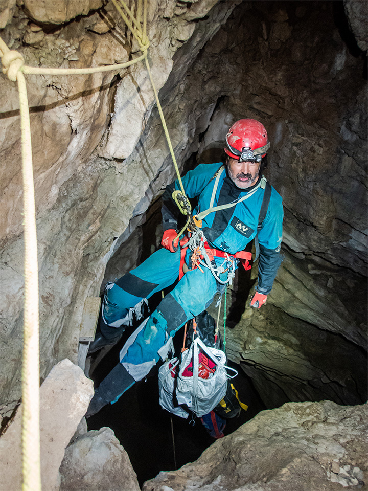 Tom Malabad carrying several cave packs in the cave.